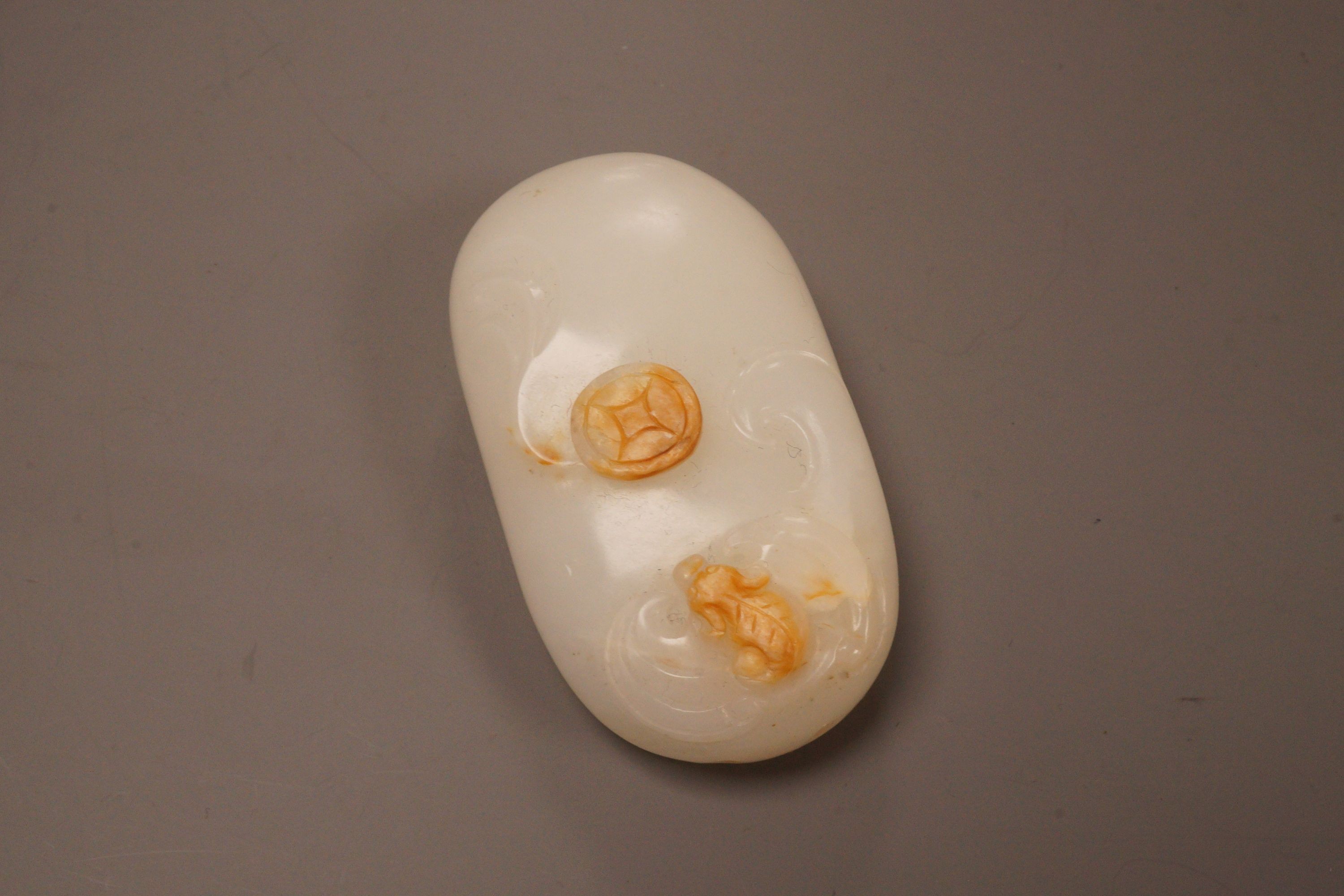 A Chinese white and russet jade pebble